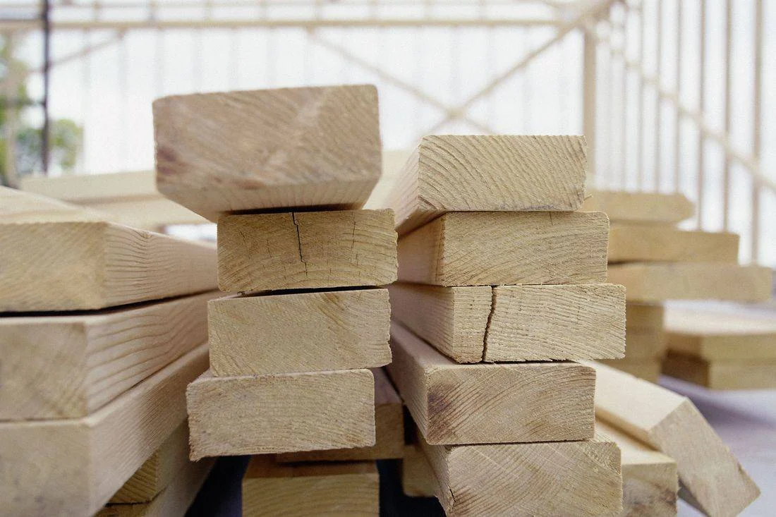 Stacked wooden blocks in a bright workshop with large windows and blurred industrial shelving