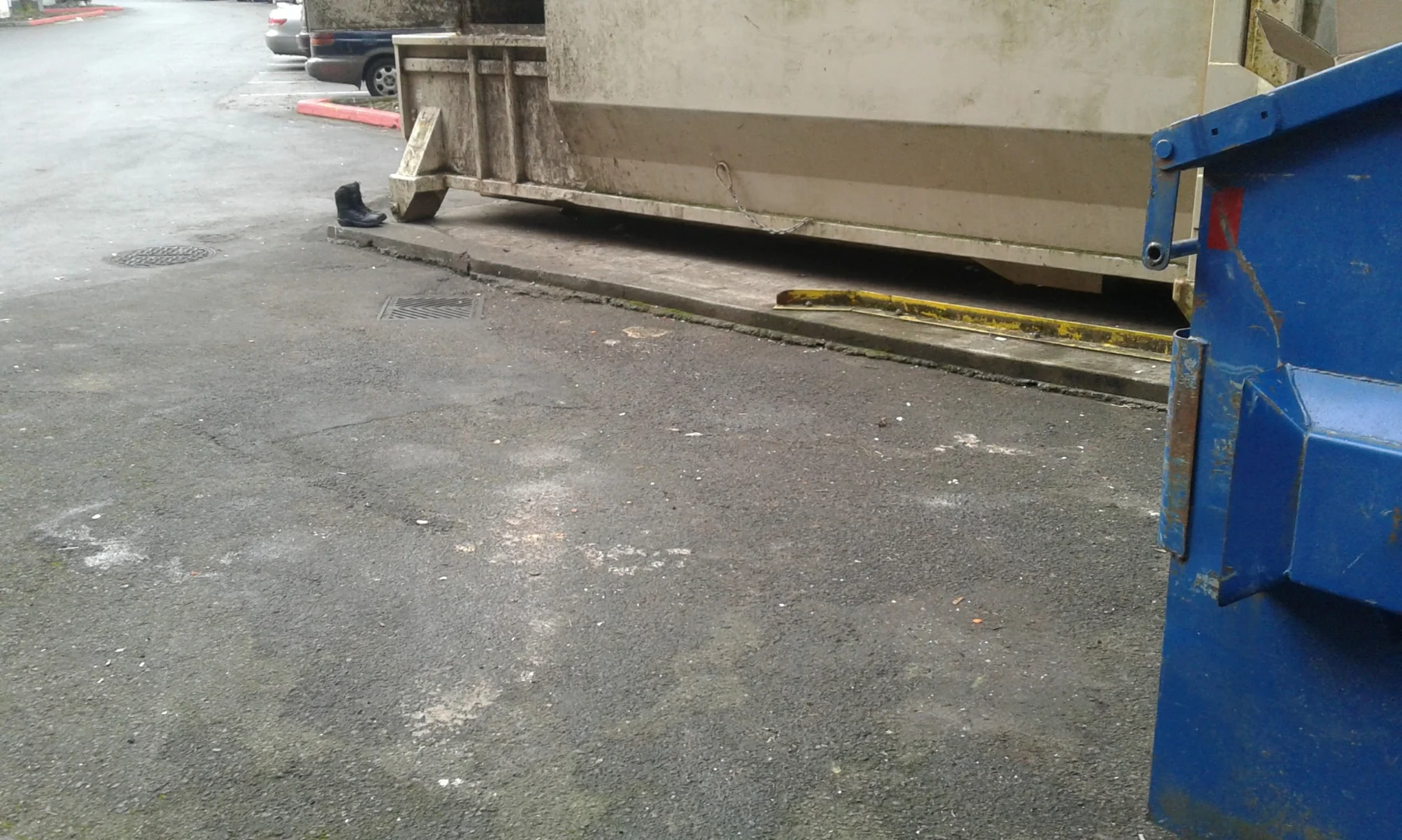 Concrete parking area with blue and beige commercial vehicles parked against a concrete building