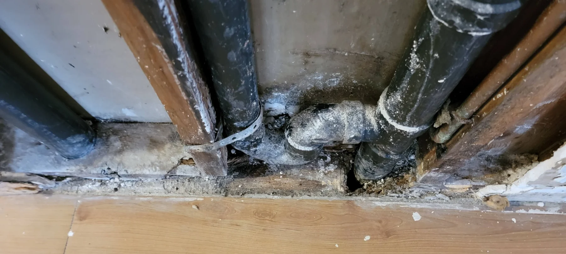 Deteriorated basement support posts with mold, water damage, and crumbling concrete foundation