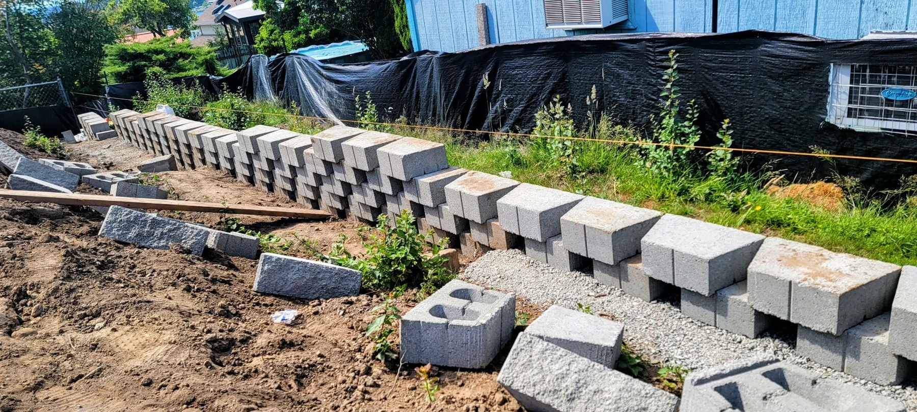 Concrete retaining wall blocks arranged in rows during construction on a residential property