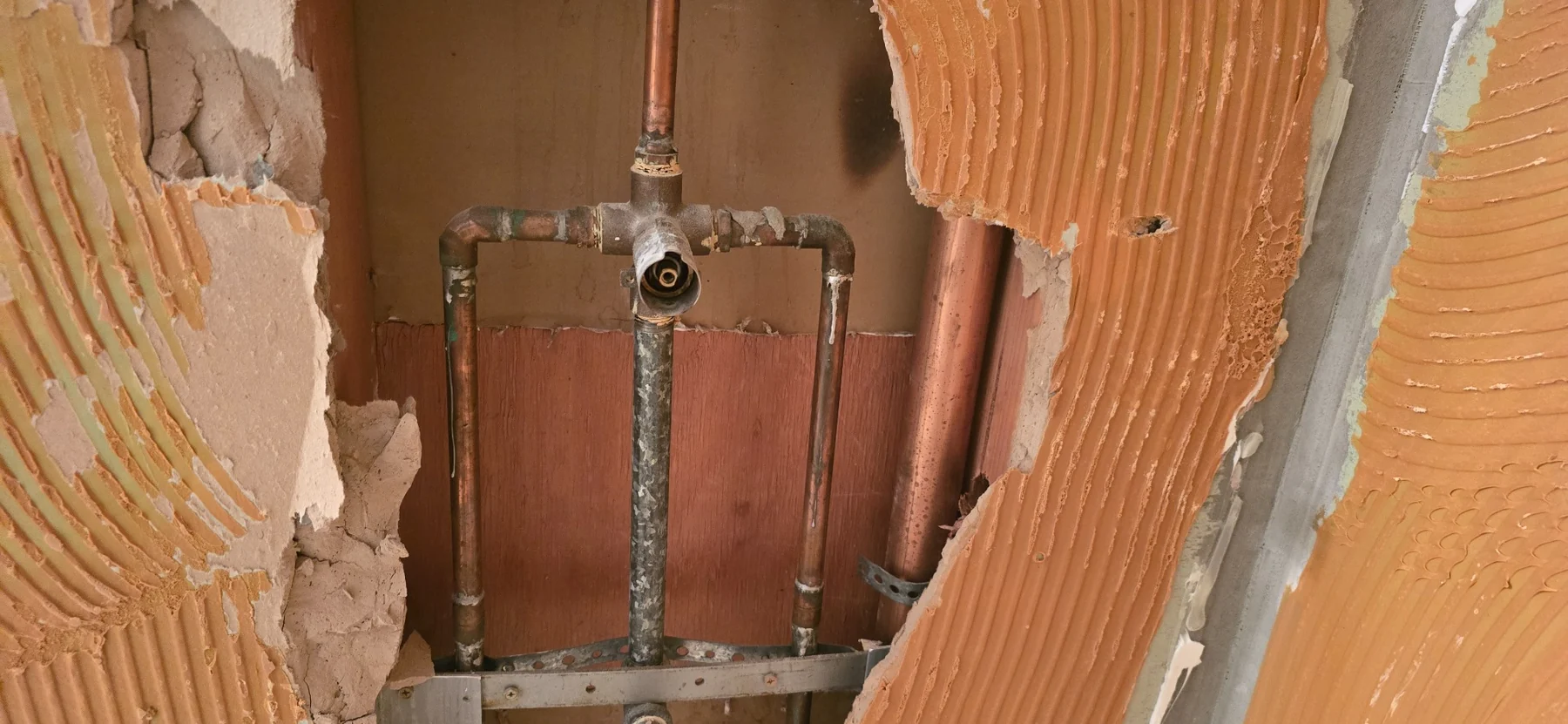 In-wall plumbing installation showing copper pipes and fitting during construction with exposed insulation