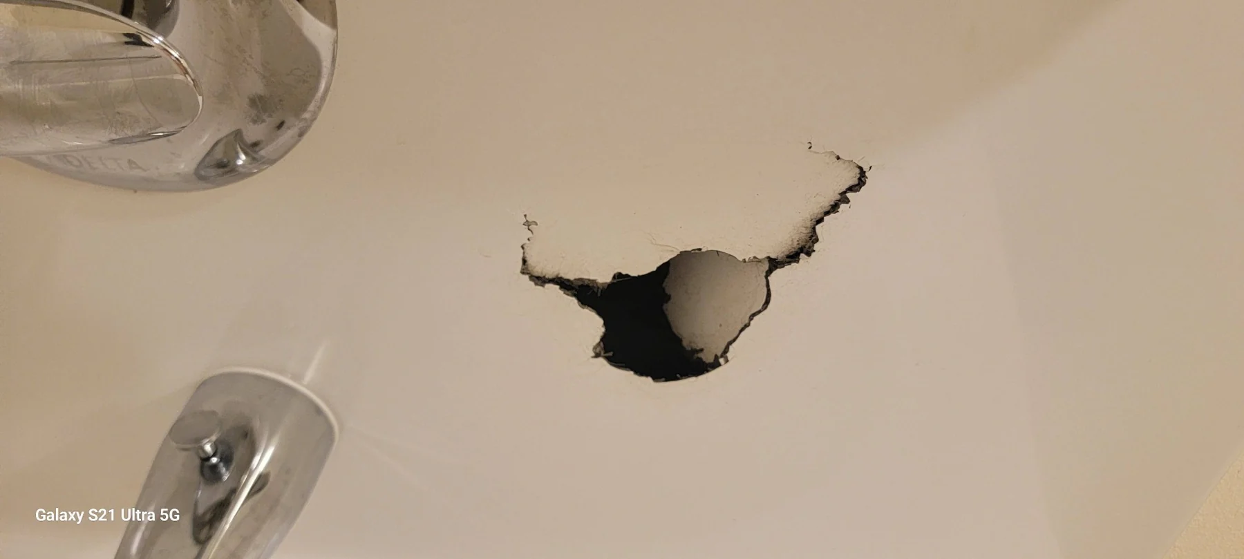 Ceiling damage with dark hole and jagged edges near light fixtures